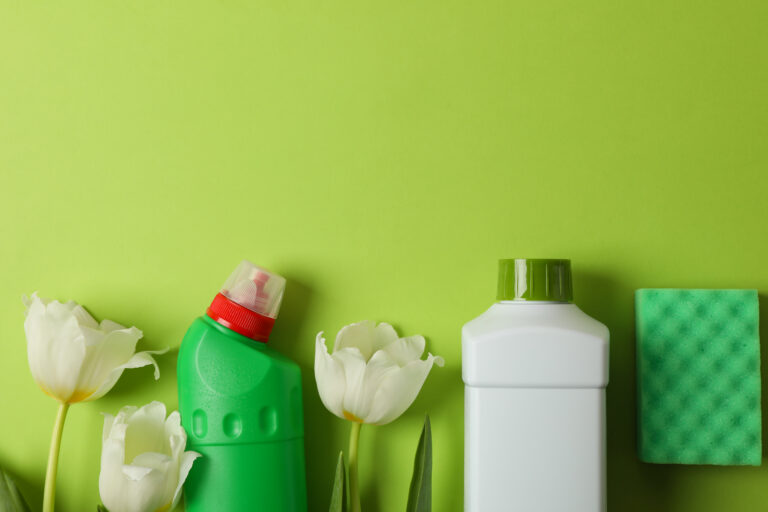 cleaning tools and tulips on green background, space for text